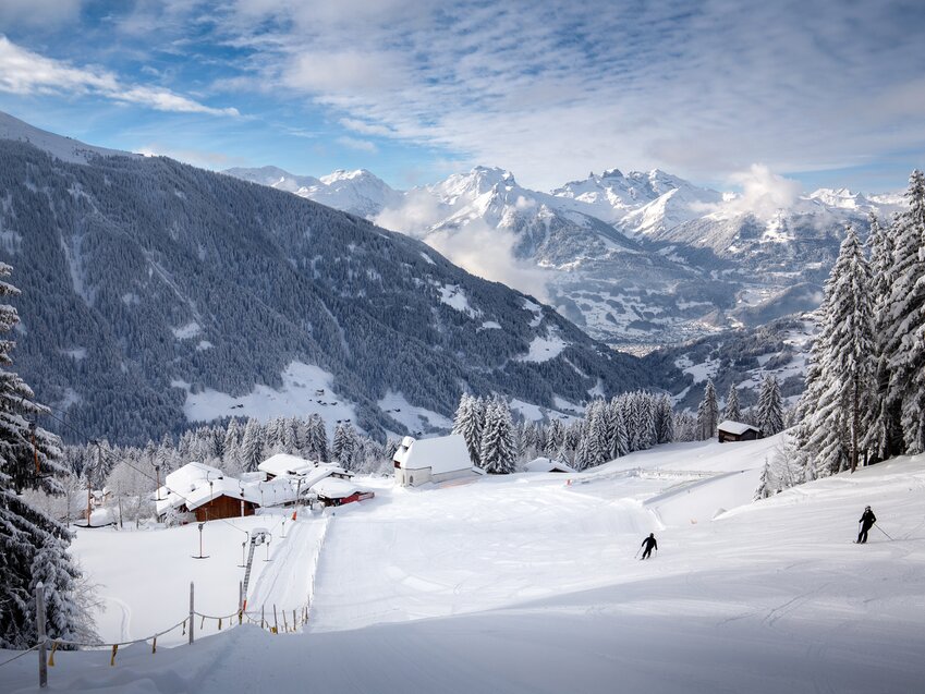 Perfectly groomed ski slope at Kristberg in Silbertal – the mountain of indulgence in the Montafon – with the snow-covered St. Agatha Church and panoramic views of the Verwall and Rätikon mountains in the Austrian Alps.